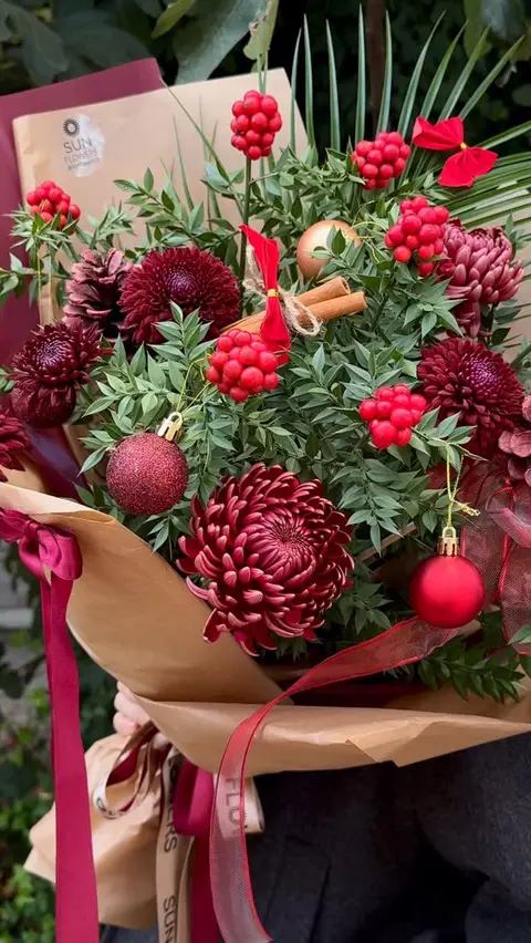 Kraft ve bordo ambalaj kağıtlarına sarılı kokinalar, çam dalları ve bordo krizantemler.