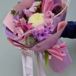 Lila ve pembe mat ambalaj kağıtlarına sarılı pembe lilyum, güller ve beyaz krizantem.