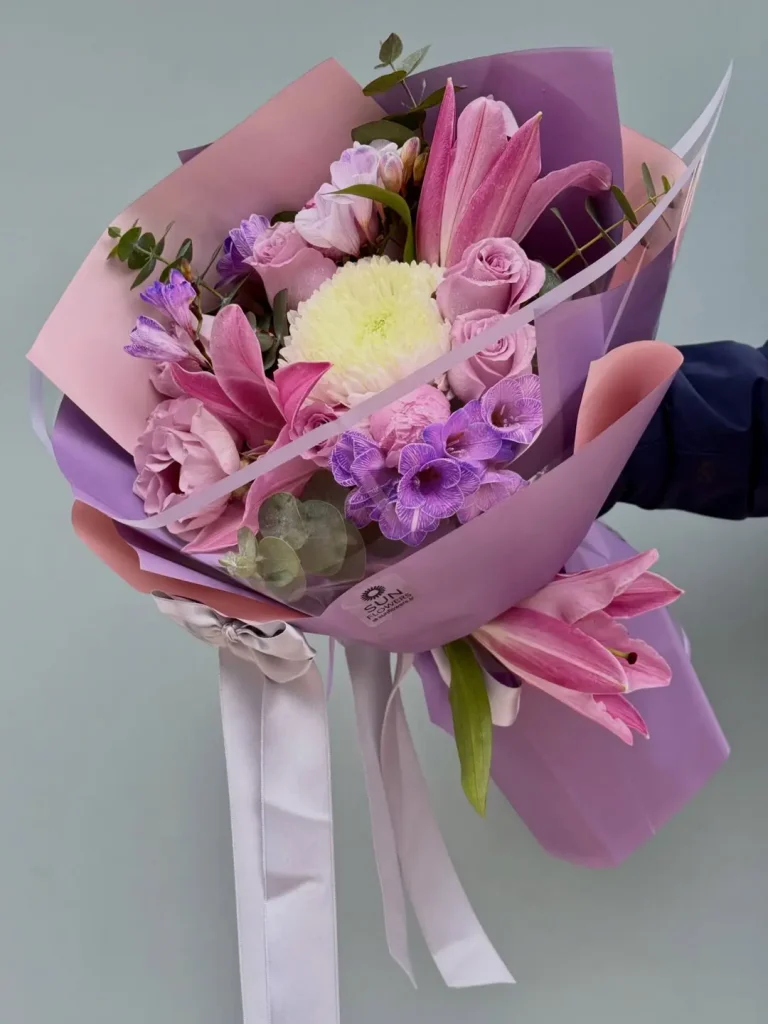 Lila ve pembe mat ambalaj kağıtlarına sarılı pembe lilyum, güller ve beyaz krizantem.