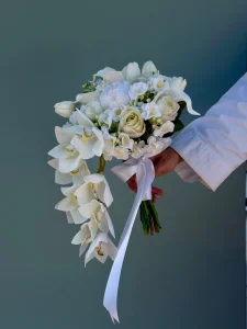 Sarkık formda tasarlanmış beyaz phalaenopsis orkide ve şakayıklardan oluşan gelin buketi