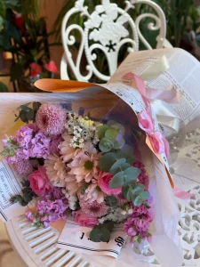 Nostaljik gazete desenli ambalaj kağıdına sarılı pembe kasımpatı ve taze gül buketi