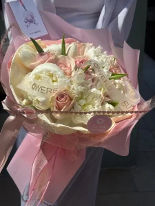 Şık toz pembe kağıt ambalajda sunulan beyaz şakayık ve pembe gül el buketi
