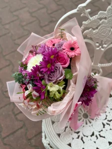 Zarif toz pembe ambalaj içerisinde pembe gerbera ve asil mor güllerden oluşan buket