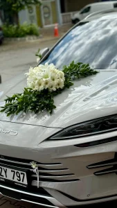 Gri BYD marka elektrikli gelin arabasının kaputunda zarif beyaz lilyum ve kasımpatı süslemesi