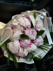 Zarif açık pembe ambalajda sunulan taptaze ıslak pembe şakayık buketi