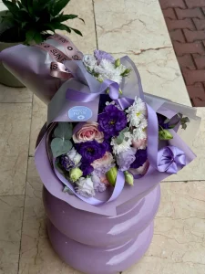 Lila ve mor ambalaj kağıdına sarılı koyu mor lisyantus pembe gül ve beyaz krizantem buketi