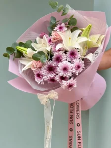 Pastel pembe ambalaj kağıdında mor hareli krizantem beyaz lilyum ve pudra gül buketi