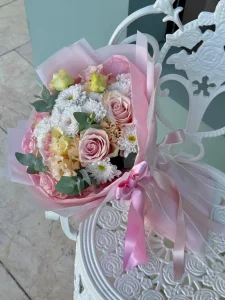 Pastel pembe ambalaj kağıdına sarılı pudra pembe güller beyaz papatyalar ve lisyantus buketi