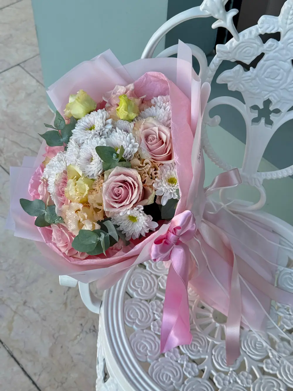 Pastel pembe ambalaj kağıdına sarılı pudra pembe güller beyaz papatyalar ve lisyantus buketi